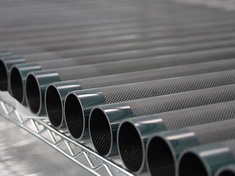 Close up image of a series of custom carbon fiber tubes tubes for Hexagon's Romer Arm laid out on an industrial shelf.